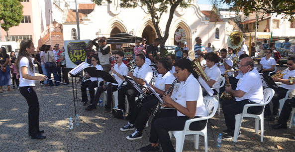 Imagem da banda Lira Santa Rita tocando na praça em frente à igreja matriz
